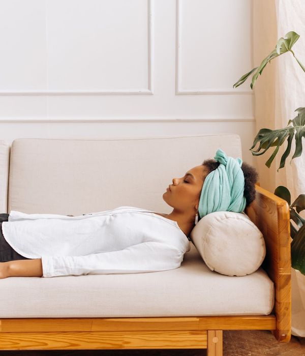 Woman in a calming yoga pose in a dimly lit room with soft light.